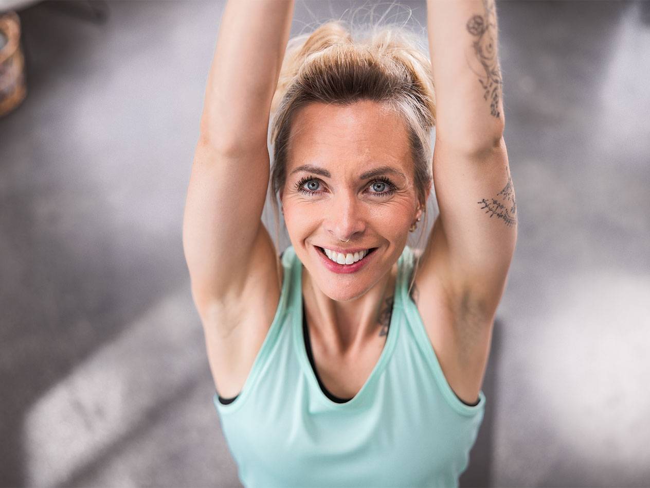 Šviesiaplaukė moteris šviesiai mėlynais marškinėliais šypsosi į kamerą.