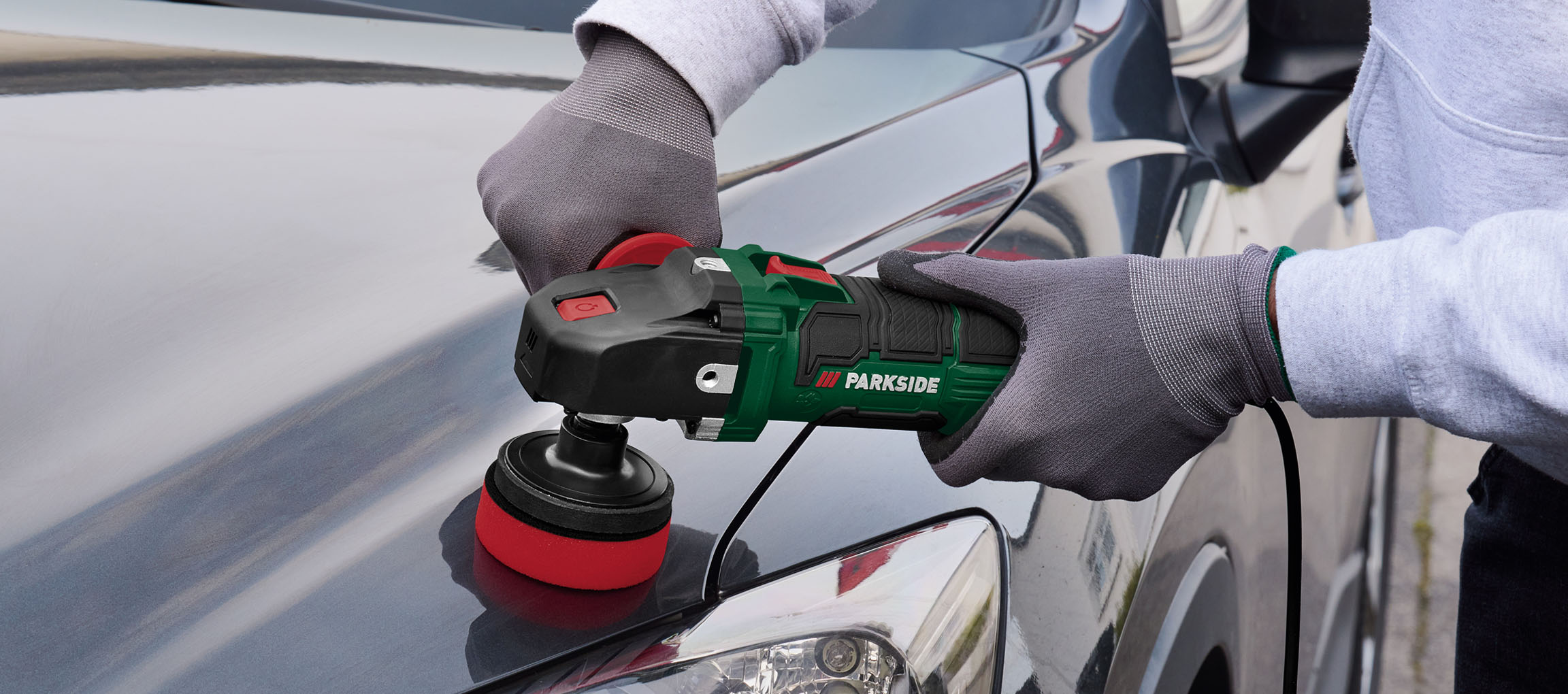 Asmuo naudoja Parkside poliravimo mašiną automobiliui poliruoti.