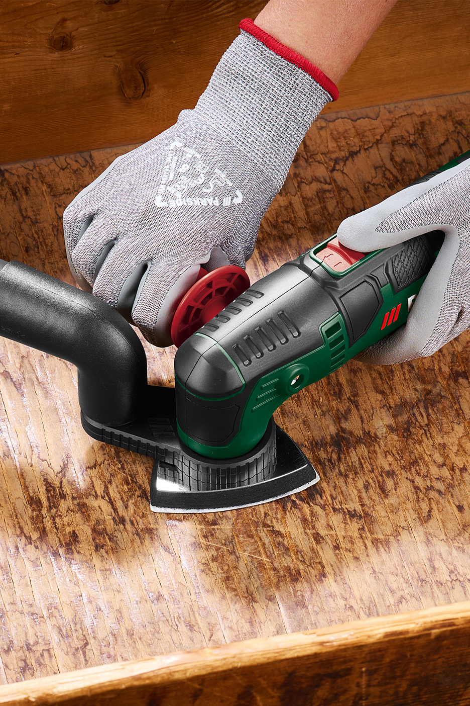 Rankos su pirštinėmis šlifuoja medieną su Parkside daugiafunkciniu įrankiu.