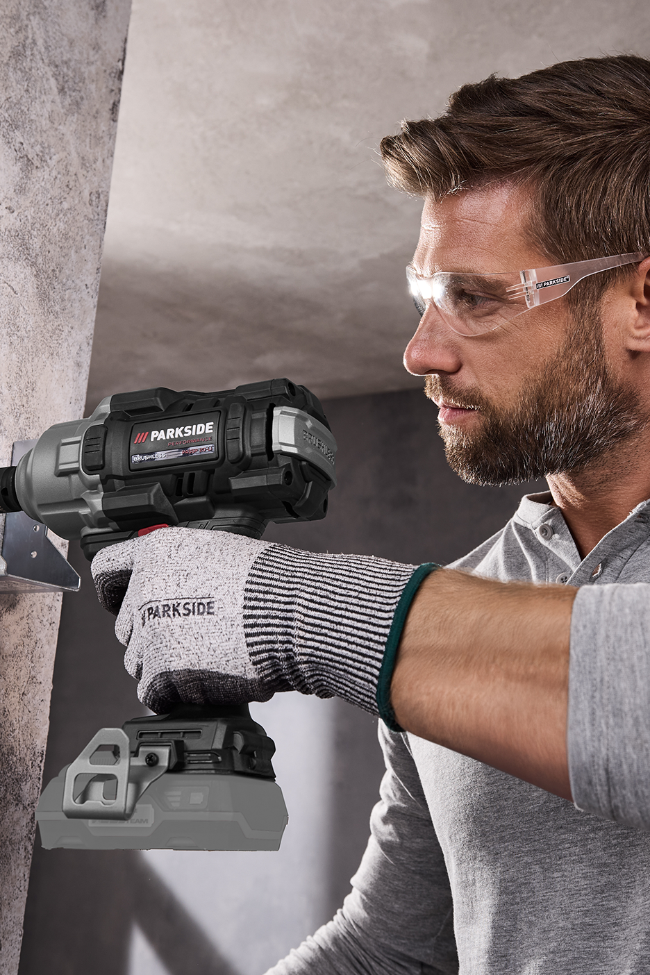 Vyras su apsauginiais akiniais ir „Parkside“ pirštinėmis naudoja „Parkside Performance“ akumuliatorinį smūginį veržliasukį.