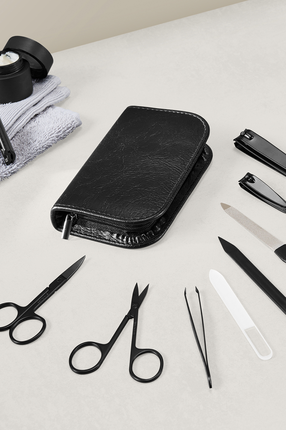 Manikiūro rinkinys su juodu dėklu, žirklėmis, pincetu ir nagų dildėmis.