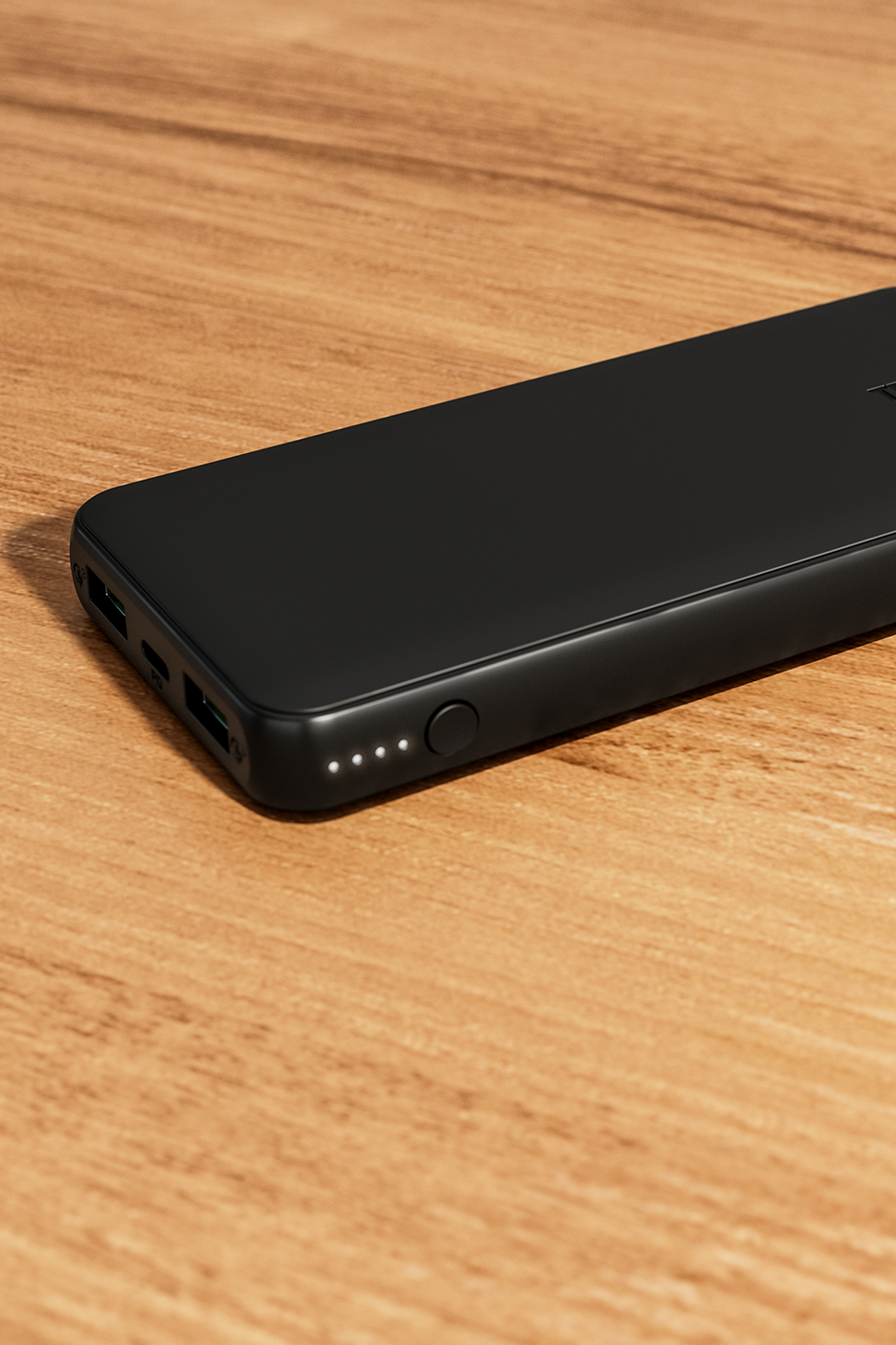 Juodas išorinis akumuliatorius su šviesos diodų indikatoriais ant medinio paviršiaus.