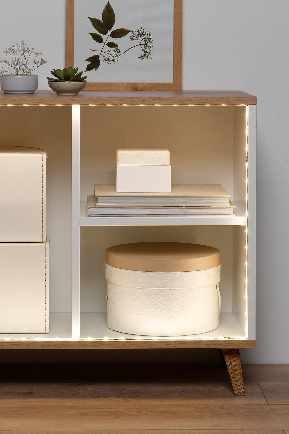 Medinė lentyna su LED apšvietimu, dekoruota augalais ir dėžutėmis.