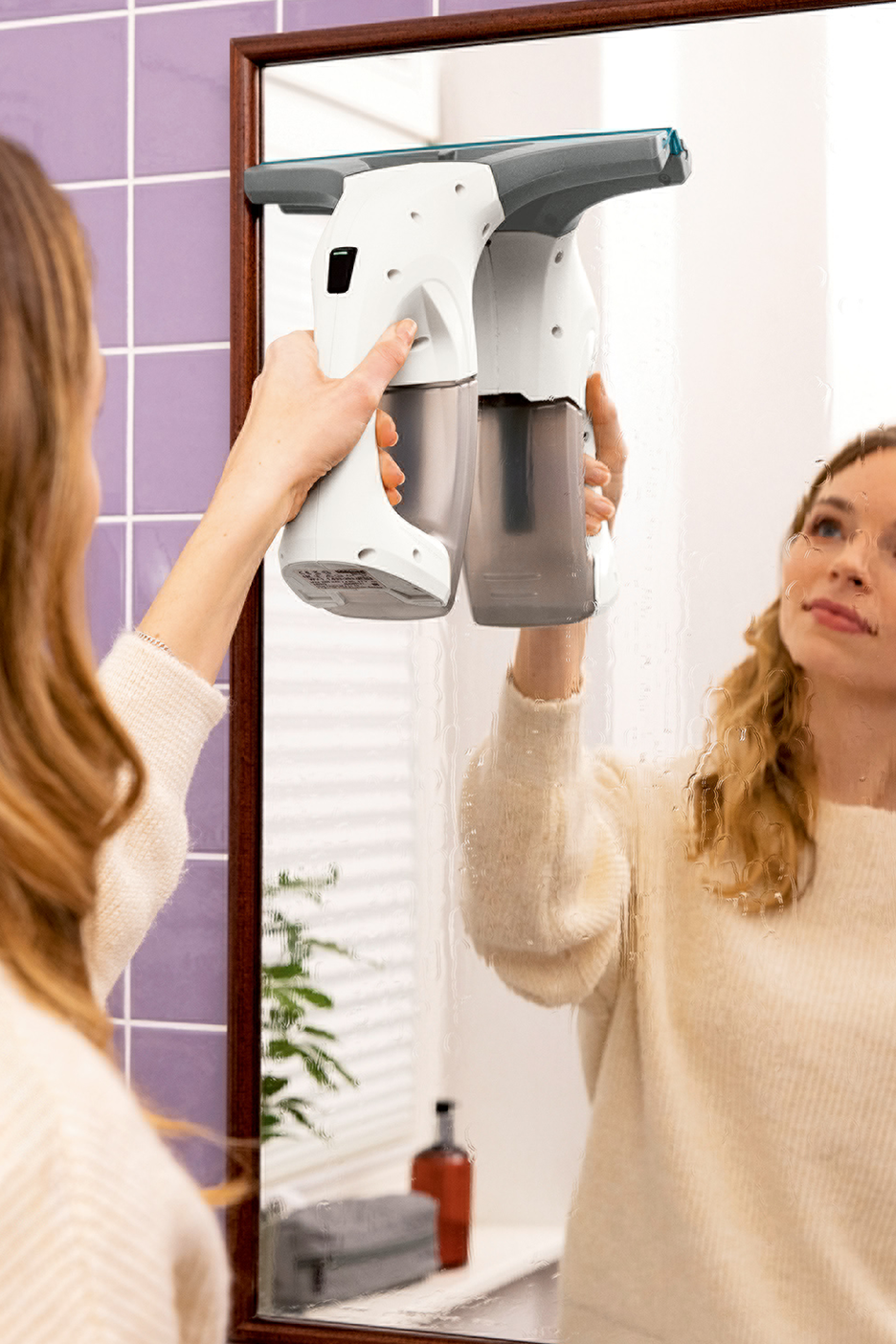 Moteris valo veidrodį su langų valytuvu.