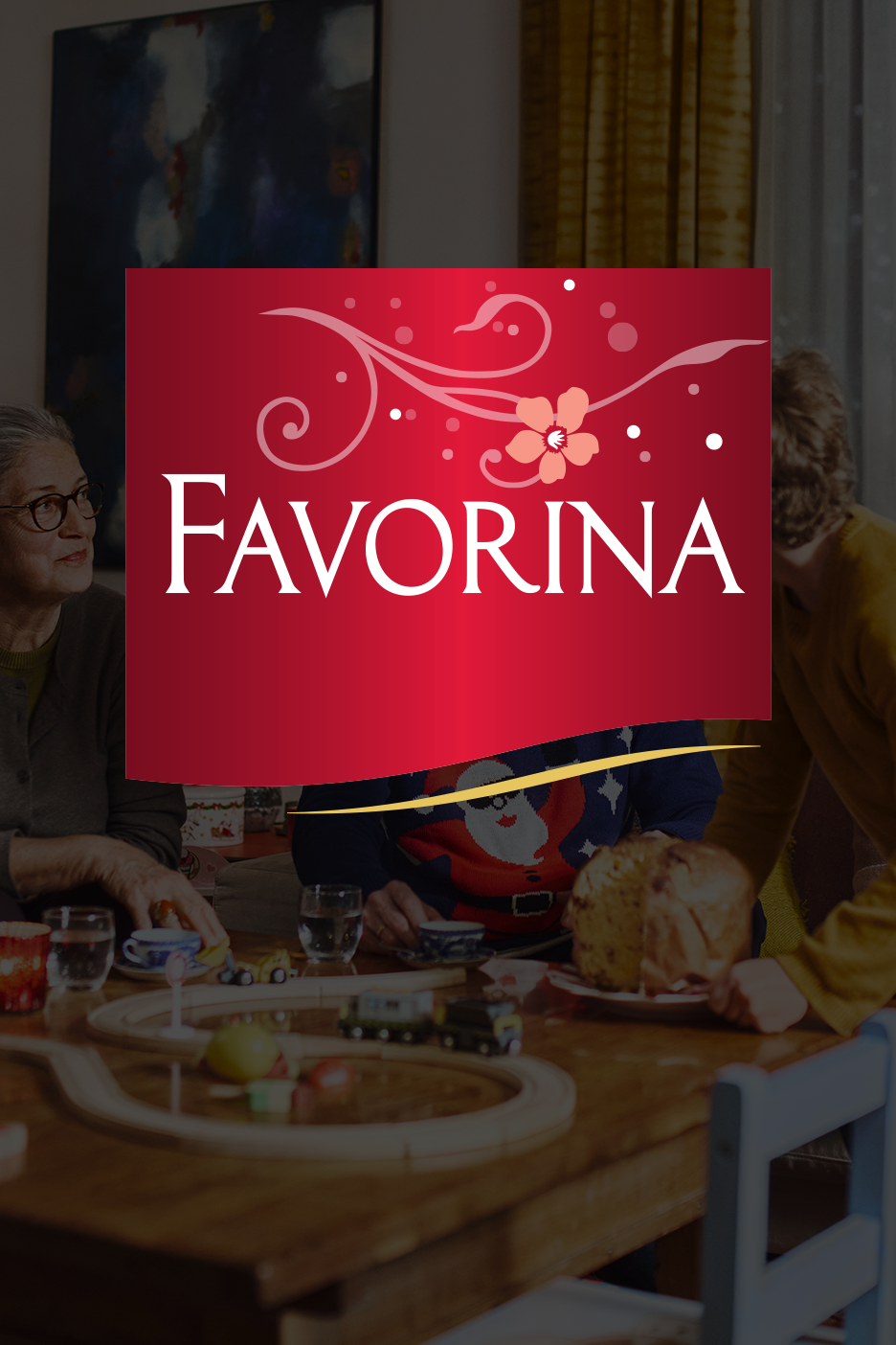 Favorina logotipas ant šventinio stalo su panettone ir žaisliniu traukinuku.