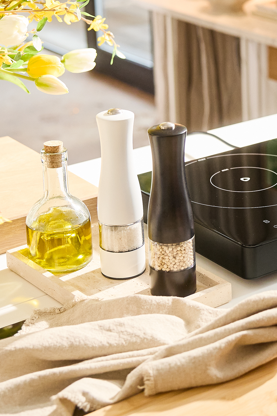 Alyvuogių aliejus, druskos ir pipirų malūnėliai ant padėklo virtuvėje.