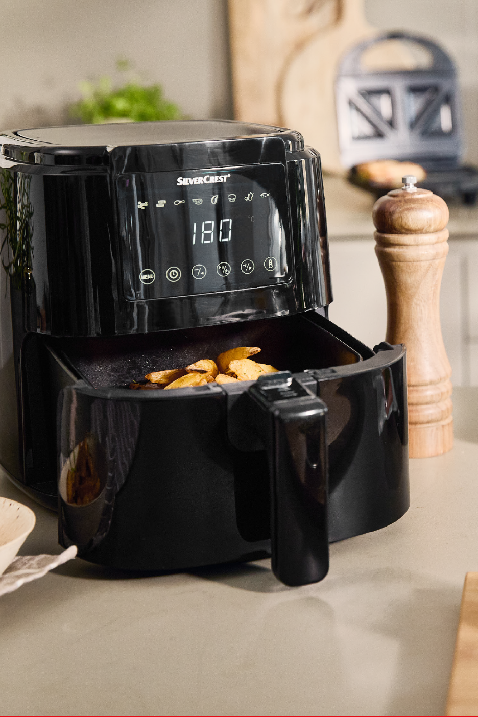 Juodas oro gruzdintuvas su traškučiais, rodantis 180 laipsnių temperatūrą.