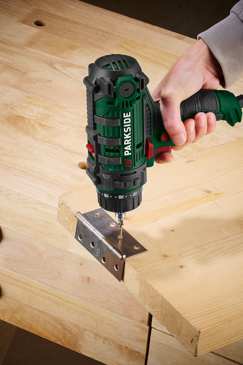 Rankinis gręžtuvas tvirtina vyrius prie medinio paviršiaus.