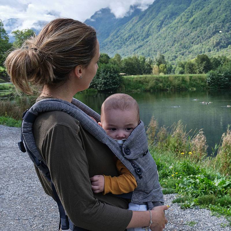 Mama su kūdikiu nešioklėje lauke.