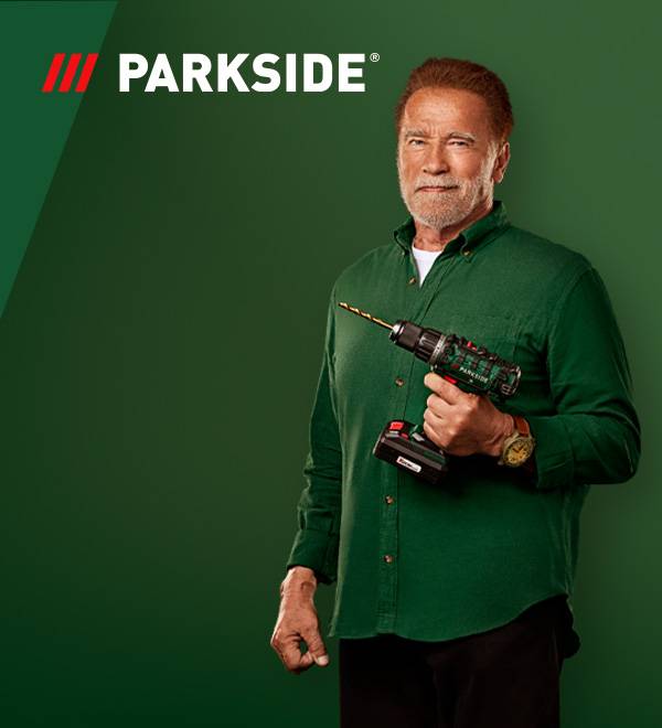 Arnoldas Schwarzeneggeris, laikantis „Parkside“ gręžtuvą, žaliame fone.