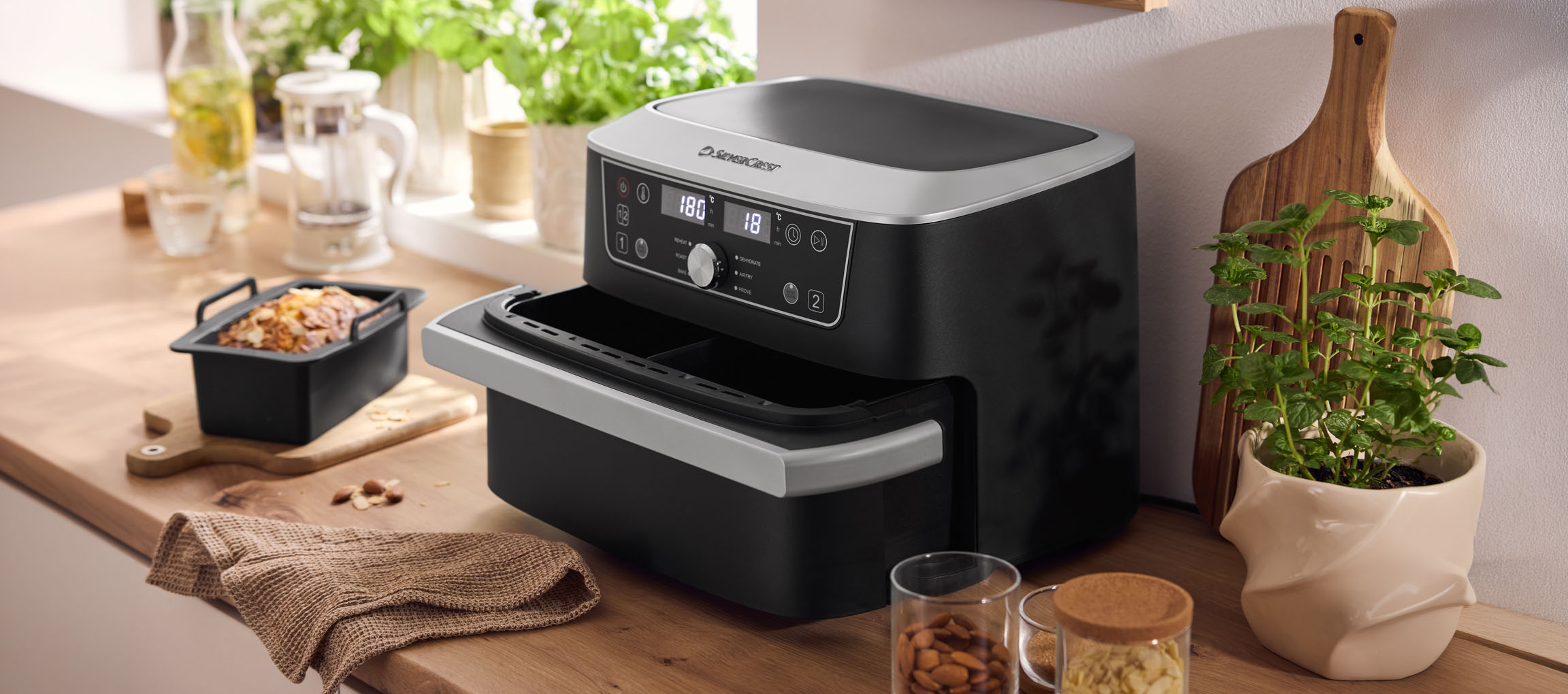 Juodas oro gruzdintuvas su dujine orkaite ir kepiniu ant medinio stalviršio.