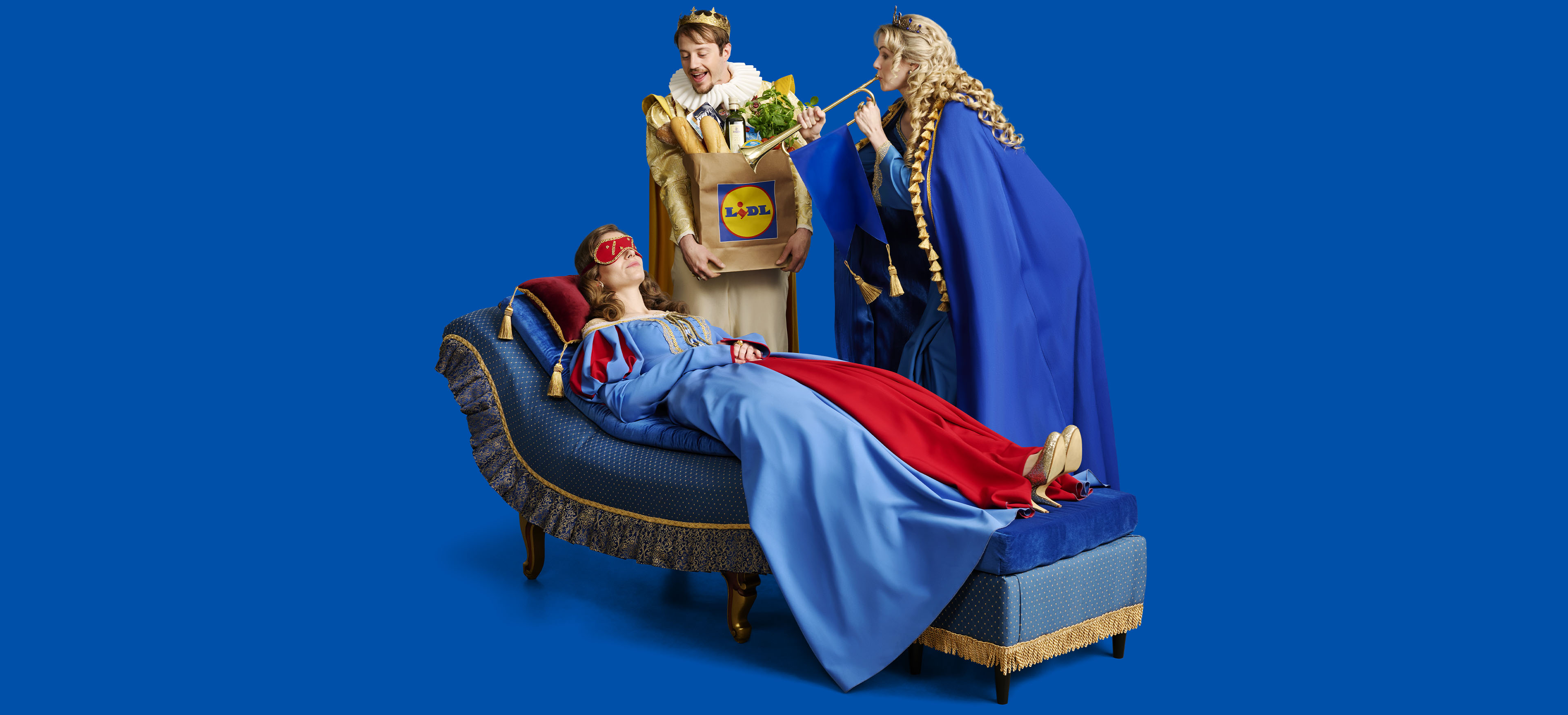 Karališkoji pora neša Lidl pirkinių maišelį, o princesė miega ant sofos.
