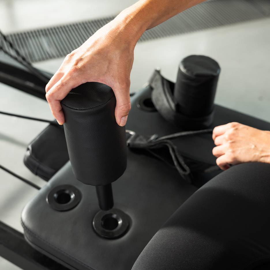 Asmuo reguliuoja juodą paminkštintą treniruoklį.