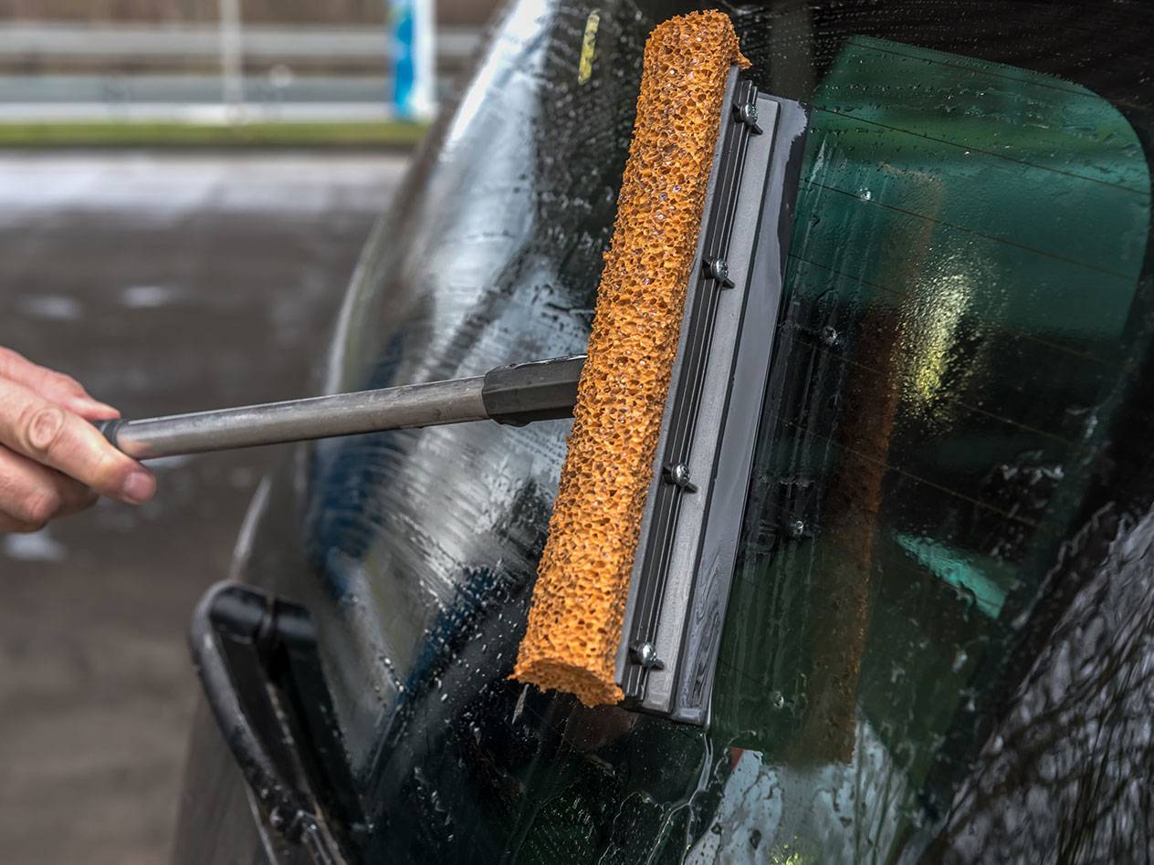 Langų valiklis su ilga rankena valo automobilio galinį langą.
