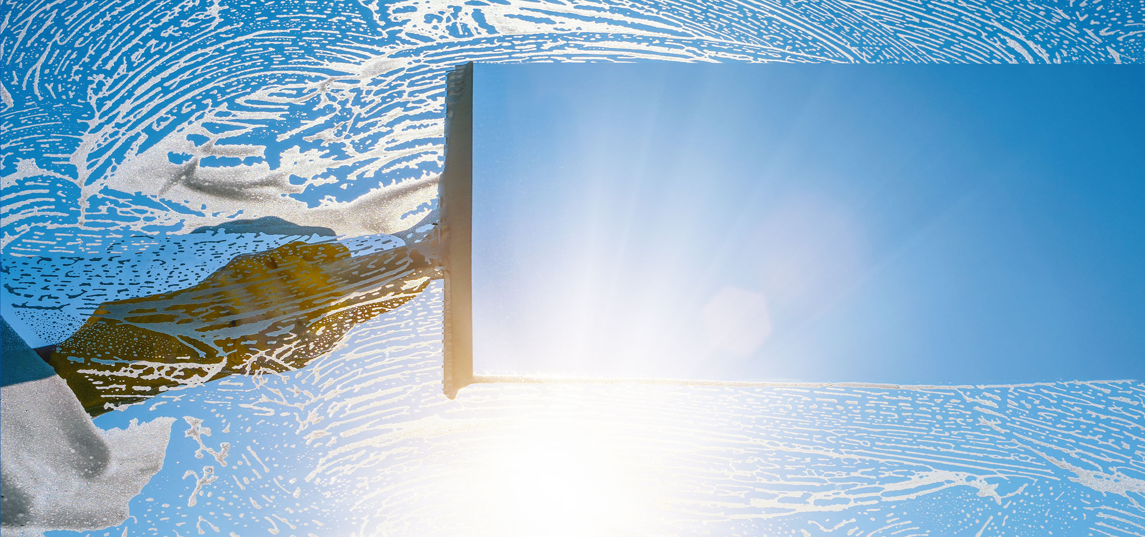 Langų valymas su muilo putomis mėlyname danguje.