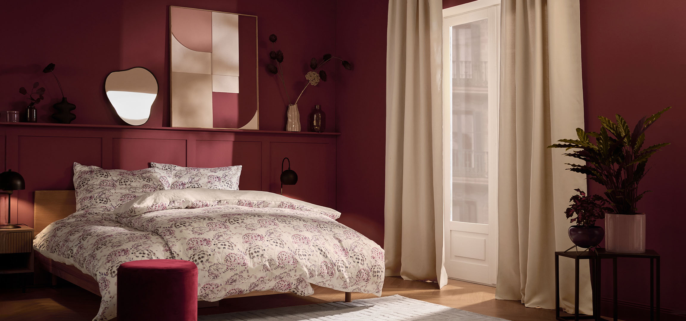 Miegamasis su bordo sienomis, lova su balta patalyne su gėlių raštu ir augalais.