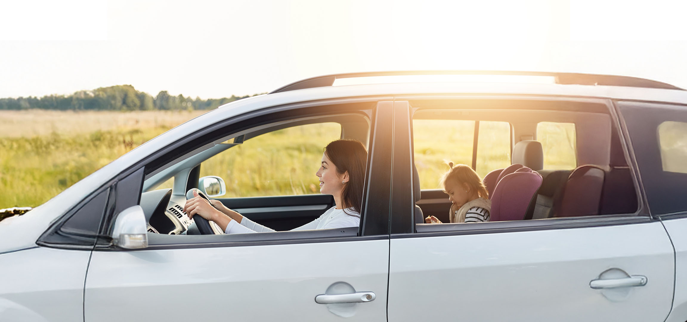 Moteris vairuoja automobilį, o jos dukra sėdi gale.