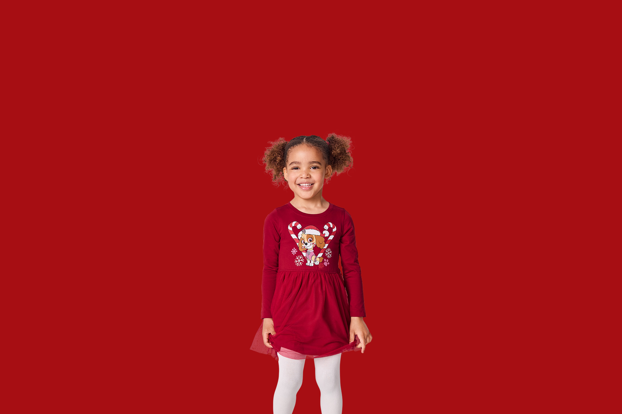 Mergaitė su raudona suknele su „Paw Patrol“ motyvu ir baltomis pėdkelnėmis