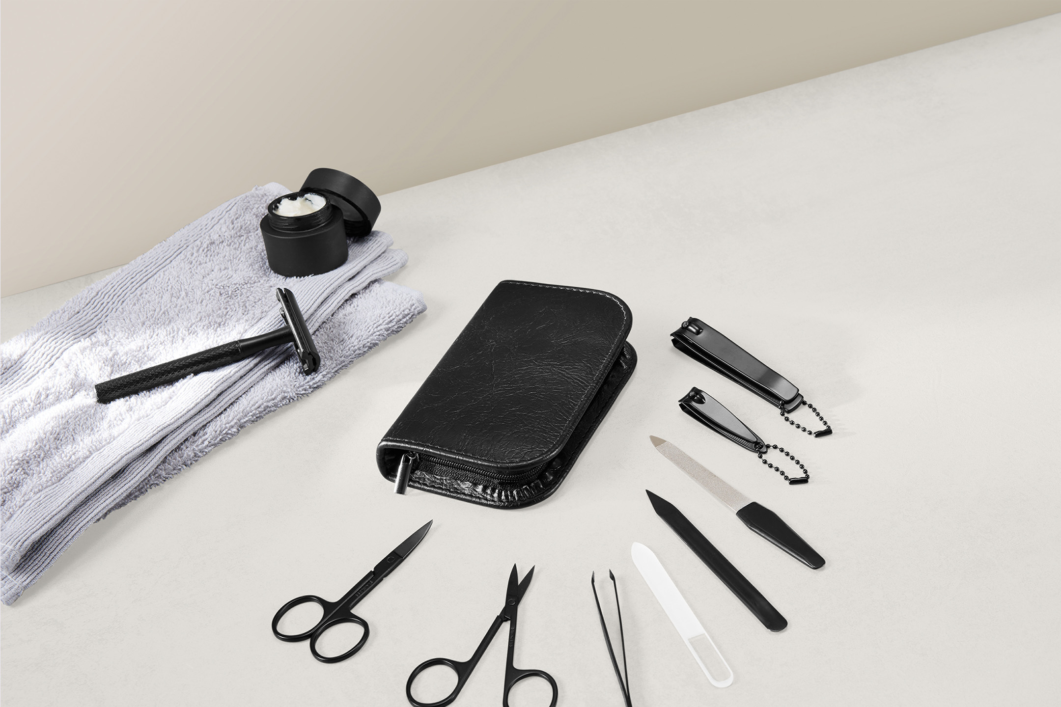 Vyriškos priežiūros rinkinys: skutimosi peiliukas, kremas, rankšluostis ir manikiūro įrankiai.