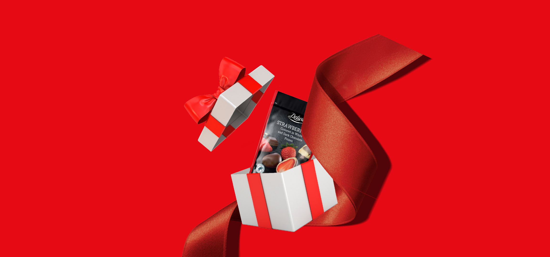 Dovanų dėžutė su „Deluxe“ šokoladu aplietomis braškėmis ant raudono fono.