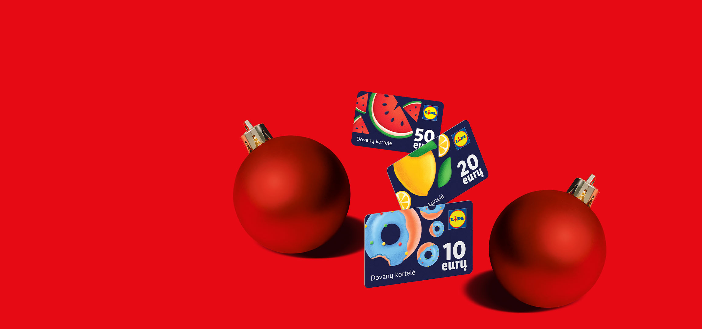 Raudonas fonas su kalėdiniu burbulu ir Lidl dovanų kortelėmis su vaisių bei spurgų motyvais.